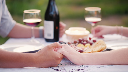 Young couple holding hands, romantic dinner with wineの写真素材