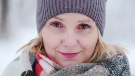 Young womans face in warm scarf against snow-covered park