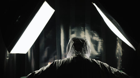 The scientist works in a secure laboratory. He's wearing a protective suit. View from behind.