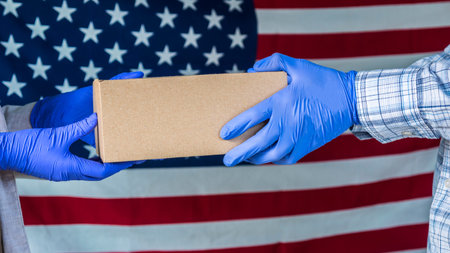 Messenger in gloves pass the parcel into the hands of the recipient against the background of the...