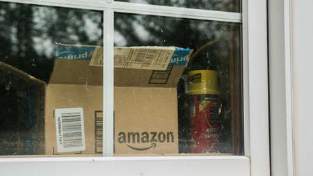 Wilson, NY, USA, July 2019: An open box from the parcel with the Amazon logo is visible outside the window.のeditorial素材
