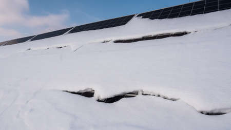 A layer of snow on the panels of a solar power plant. Green energy problems and weather dependenceの写真素材