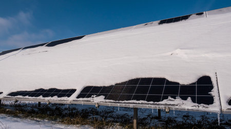 A layer of snow on the panels of a solar power plant. Green energy problems and weather dependence