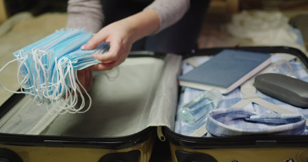 The traveler packs many protective masks in their luggage.
