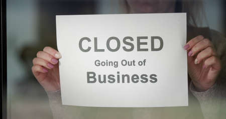 Worker hangs a banner CLOSED going out of Business on the doorの写真素材