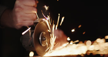 Hands of a worker with a power tool, grinding metal, sparks fly to the sides