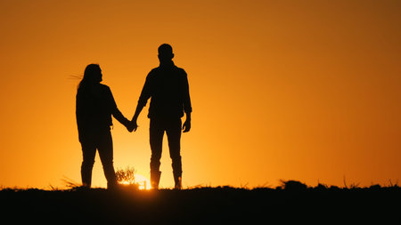 Young couple admiring the sunset over a field