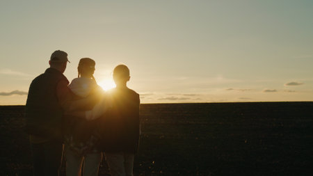 A family of farmers admires the sunset in their own fieldの写真素材
