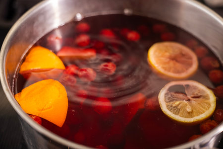 A pot of homemade fruit compote with orange slices, lemon slices, and berries simmering in water.の写真素材