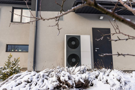 Modern heat pump unit outside a house in winter, providing energy-efficient heating in cold weather.の写真素材