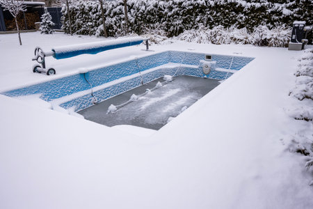 Winterized swimming pool covered in snow with protective floats preventing freeze damage.の写真素材