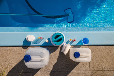 Swimming pool edge with cleaning equipment and maintenance products including chemical canisters, chlorine tablets, dispenser, test kit and submerged vacuum brushの写真素材