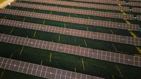 Aerial view of a solar power station with rows of photovoltaic panels arranged symmetrically on...