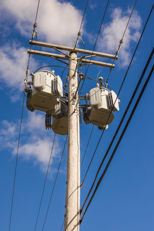Electric pole with multiple transformers and power lines under blue sky in the United States