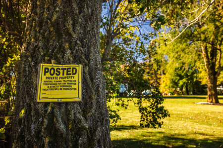 Yellow warning sign posted on a tree trunk in a rural areaの写真素材