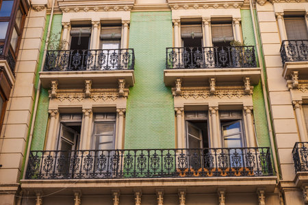 Historic Art Nouveau facade with decorative balconies and green ceramic tiles in Alicante, Spain