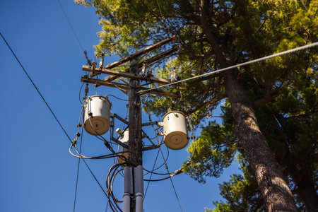 Utility pole with power transformers and cables against clear blue sky in the United States