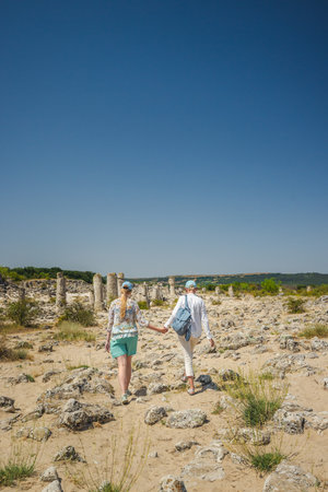 Two women holding hands while exploring the natural stone formations of Pobiti Kamani near Varna, Bulgaria, on a sunny summer day.の写真素材