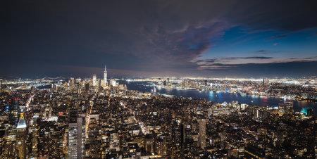 Night view of New York City skyline with glowing skyscrapers and reflections on the Hudson Riverの写真素材