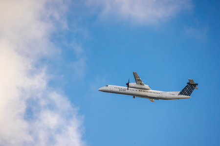 Toronto, Canada, October 20: Porter Airlines turboprop aircraft flying through a blue sky with scattered clouds during daytime.のeditorial素材