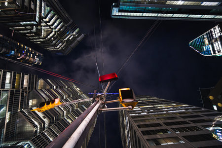 A lone traffic signal rises into a canyon of towering glass, its red glow contrasting with the cold...