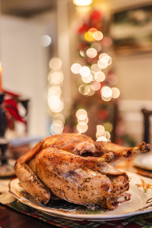 Roasted holiday turkey served on a festive table with warm Christmas lights glowing in the background.の写真素材