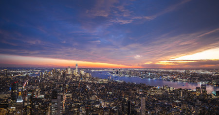 New York City skyline at twilight with illuminated buildings and colorful sunset sky over the Hudson...