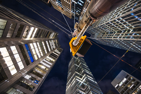 Night view looking up at illuminated skyscrapers with overhead transit wires and a traffic signal.の写真素材