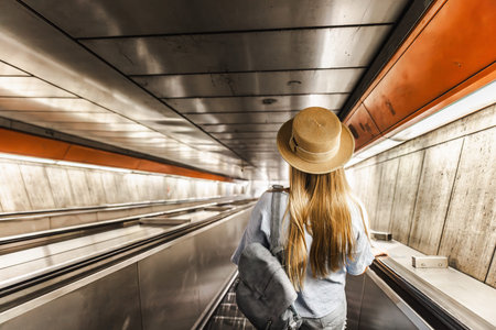 Young woman descending escalator in metro tunnel, urban travel and public transportation concept