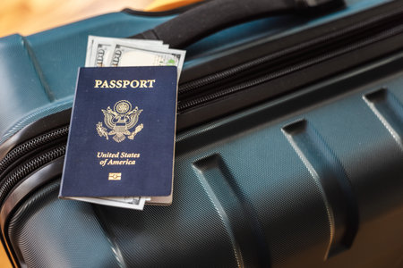 US passport with dollar banknotes on travel suitcase symbolizing international travel and moneyの写真素材