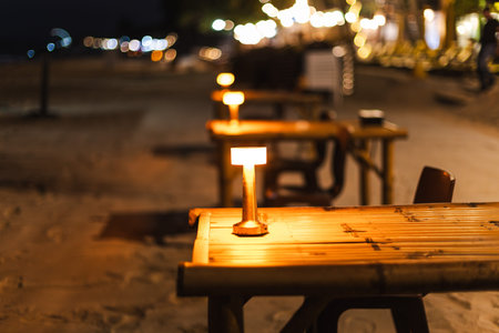 Row of illuminated tables at beach restaurant at night on tropical island