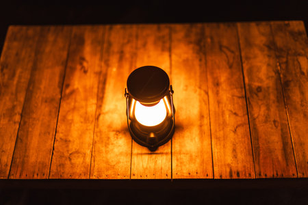 Warm glowing lantern on wooden table at night tropical beach restaurant
