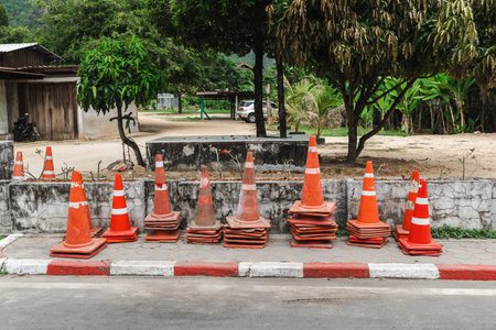 Stack of orange traffic cones on roadside near village street on Koh Samui Thailand