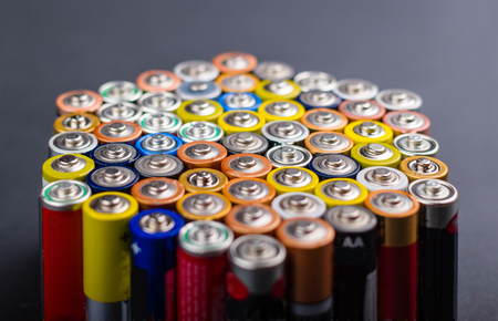 Battery AA texture blurred in a row. Defocused rows of batteries, perspective view. Multicolored batteries AA, cell row hexagon organizedの写真素材
