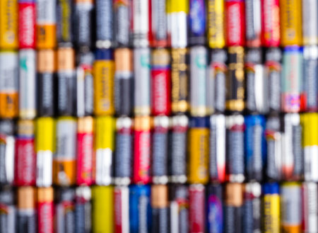 Battery AA texture blurred in a row. Defocused rows of batteries, top view. Multicolored batteries AAの写真素材