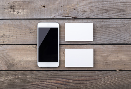 Photo of business cards with phone. Template with smart phone isolated on old wood background. For graphic designers presentations and portfolios damaged weathered antique mock-up with business cardsの写真素材