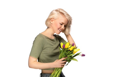 Woman smiling holding bouquet of tulip flowers, studio portrait isolated on white backgroundの写真素材