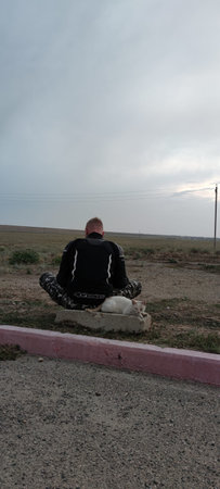 Young pensive male motorbike driver sits near road, enjoys good rest and wonderful nature view. Transport and lifestyle conceptのeditorial素材