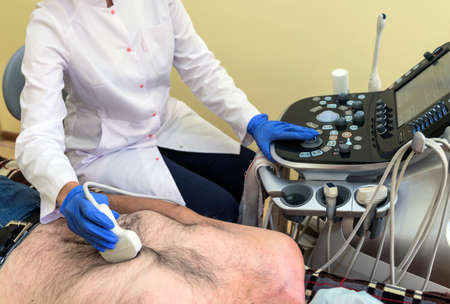 A patient in the clinic examines his abdominal cavity while lying on the bed.の写真素材