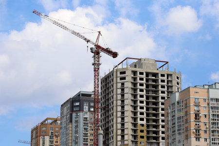 One tower crane building one multi-storey house on clear sky background. Construction industry. City...