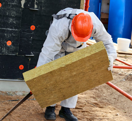 A builder measures the area wearing helmets, goggles and protective equipment at a construction site...