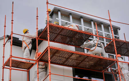 A lone pigeon bird sits on the building forests. Construction scaffolding on the front of the building. Equipment for high-rise work. Work at altitudeの写真素材