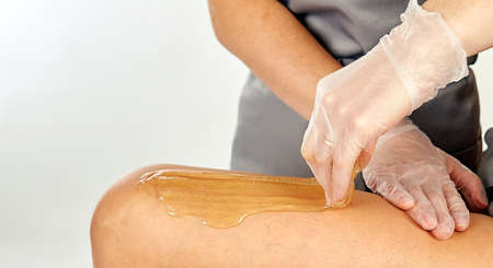 Sugar paste for light depilation. Depilation with sugar paste in the salon on a white background.の写真素材