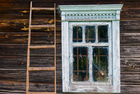 Old European wooden window in an old house. Wooden ladder on the wall.の写真素材