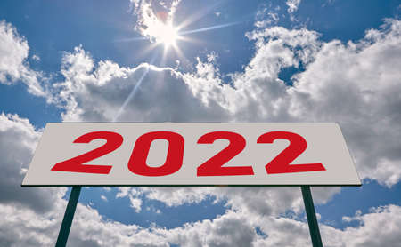 Year 2022 is written on a highway in the middle of an empty asphalt road and a beautiful blue sky. Road sign on a background of the sky.の写真素材