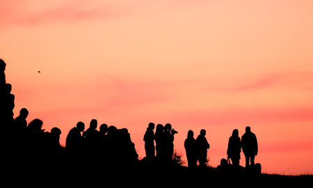 Silhouettes of people with different expressions on the embankment of the sea sunset.