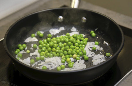 Green peas in the kitchen in a pan. Preparing a side dish for dinner.の写真素材