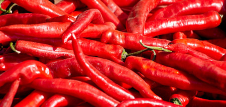 Red chili peppers with vegetables in the market. Tomatoes and peppers are selected by the buyer at...