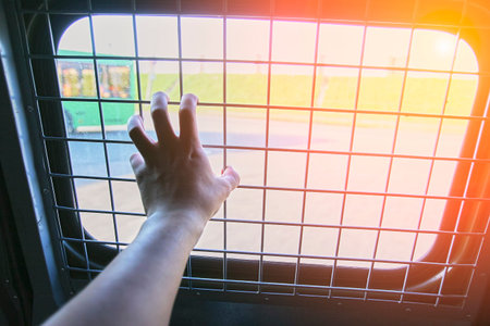 Man in prison hand holding a steel cage prison bars. criminal criminal is locked in prison. The hand...