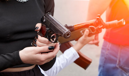 Children's hands on a rifle or machine gun. Rifle barrel. The girl is holding a Makarov pistol in her hands.の写真素材